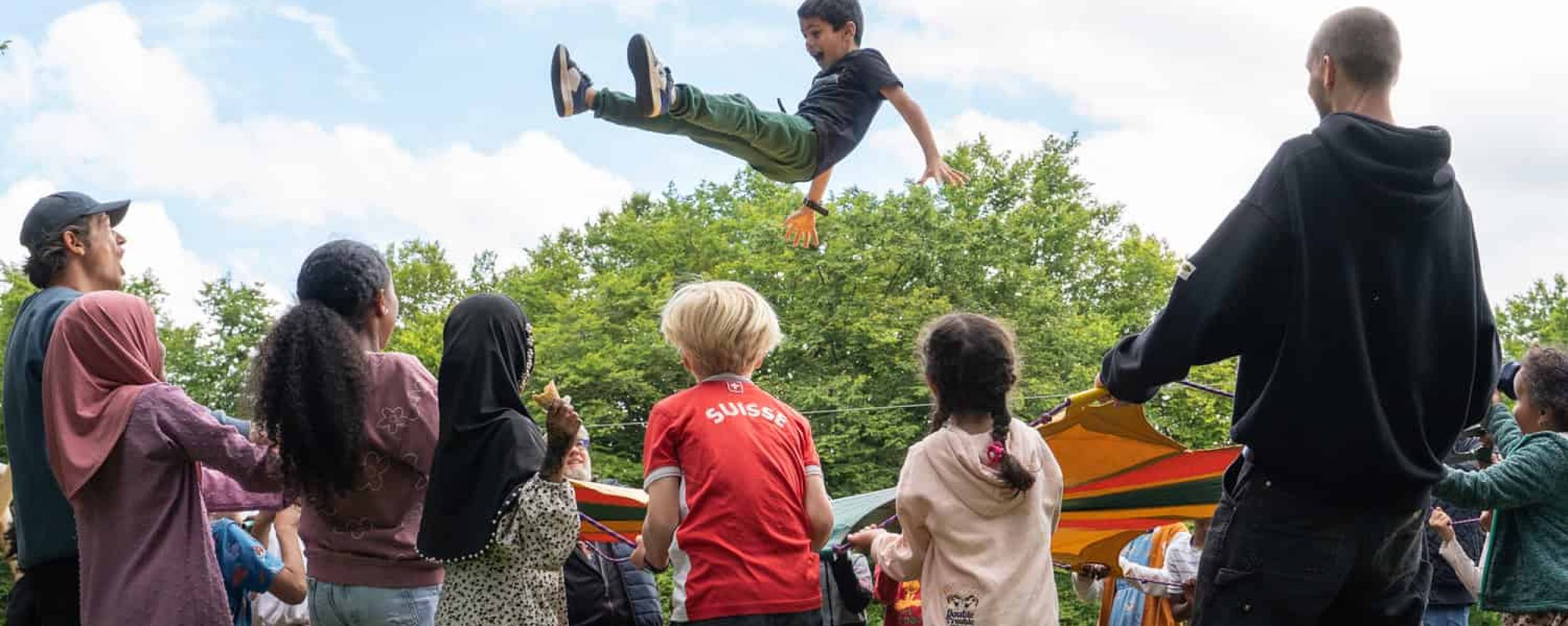 Kinder spielen am Jubliäumsfest der SFW mit Springtuch.